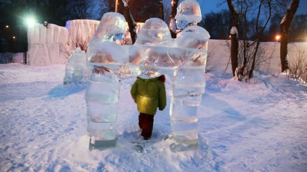 Meisje gaat soms door poort in vorm van beeldhouwwerken van het ijs vertegenwoordigen van man en vrouw — Stockvideo