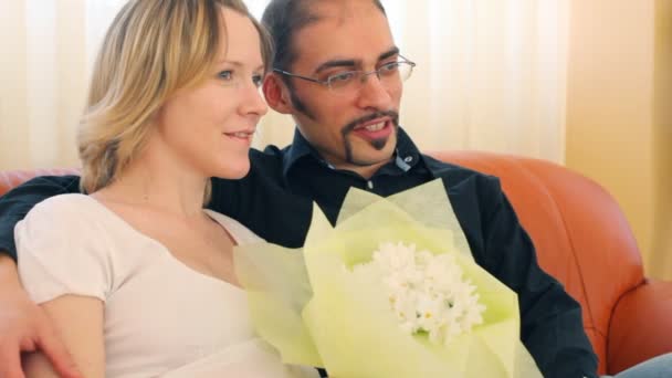 Homme et femme avec un bouquet de fleurs assis sur divan — Video