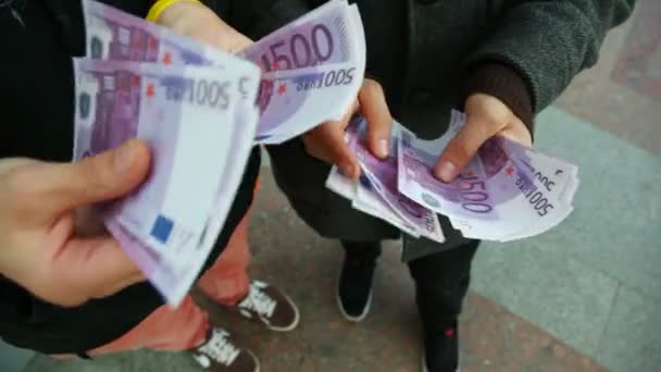 Руки двух молодых людей пересчитывают счет на пятьсот евро — стоковое видео