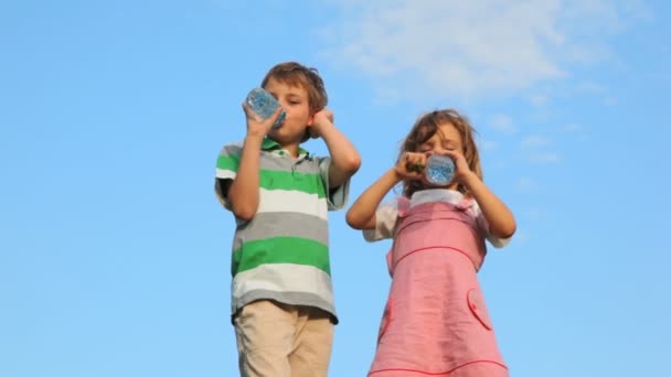 Menino com menina de pé e beber água de garrafas de plástico — Vídeo de Stock