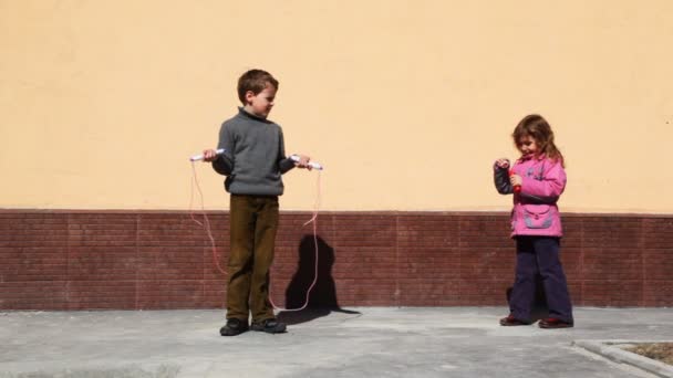 Boy jumping em pular corda e menina inflar bolhas de habitação — Vídeo de Stock