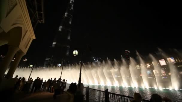 Los turistas miran las fuentes muestran cerca de rascacielos noche Burj Khalifa en Dubai, Emiratos Árabes Unidos . — Vídeos de Stock