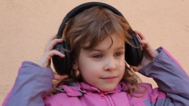 Девушка надевает наушники, слушает музыку и танцует — стоковое видео