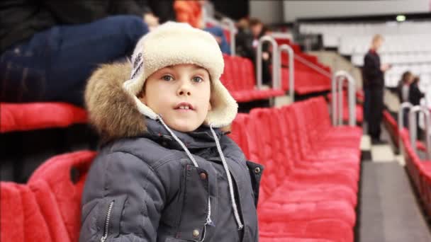 Niño se sienta en sillón, atentamente ver partido de hockey — Vídeo de stock