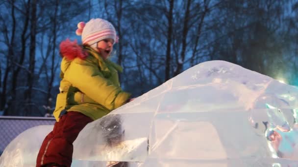 Girl sits on ice sculpture, slides off downwards, father lifts it — Stock Video