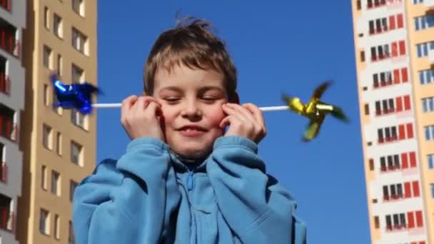 Chłopiec umieścić jego policzka dwie zabawki wiatrak — Wideo stockowe