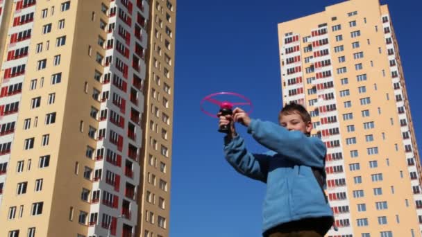 Jongen loopt speelgoed helikopter tegen achtergrond — Stockvideo