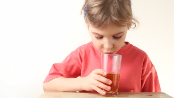 Kleines Mädchen trinkt Orangensaft und lächelt — Stockvideo