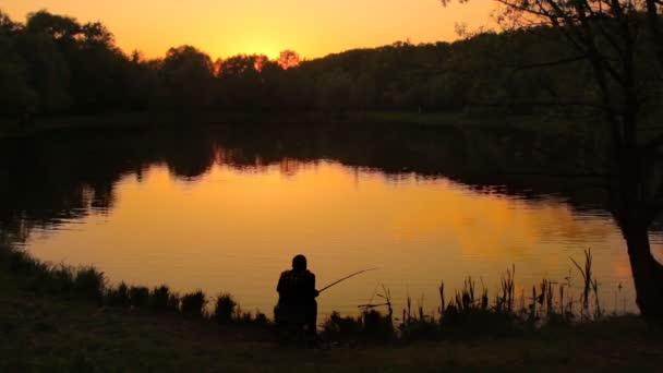 Widok człowieka siedzi w pobliżu wody i połowów z tyłu — Wideo stockowe