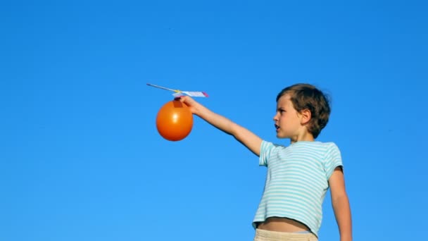 Niño lanzando bola con tornillo de aire contra el cielo — Vídeos de Stock