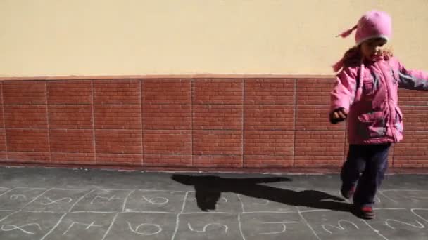 Fille filant sur l'asphalte avec photo de jeux de marelle — Video