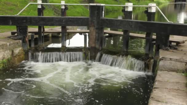 Fluxo claro calmamente correndo por pedras e boa sluice feita de madeira — Vídeo de Stock