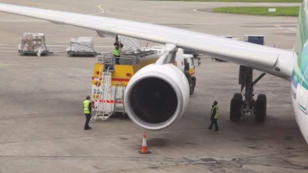 Avión de pie en la pista de aterrizaje está lleno de combustible por equipo de servicio — Vídeos de Stock