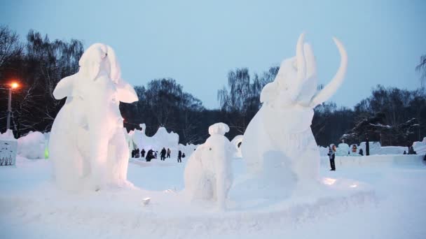Snow sculptures of mammoths at winter evening on snow small town — Stock Video