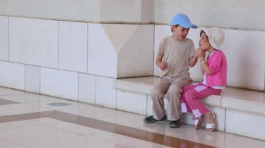 küçük kız ve erkek duvara yakın oturur