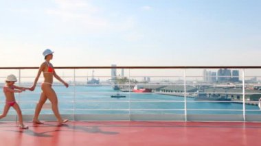 Anne ve kızı bikini gemi güvertesinde yürür
