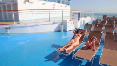 Anne ve kızı bikini şezlonglar üzerinde yalan