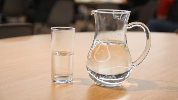 Copa y jarra llena de soporte de agua en la mesa en la sala de conferencias — Vídeos de Stock