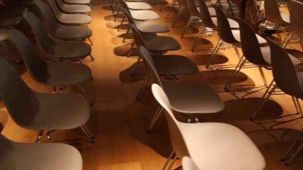 Vista si sposta da sedie marroni vuote a una con giornale in cima in qualche sala conferenze — Video Stock