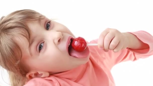 Little girl eating lollipop, then looks at camera — Stock Video