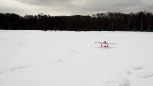 Παιχνίδι τηλεκατευθυνόμενο αεροπλάνο που πετά επάνω από χιόνι — Αρχείο Βίντεο