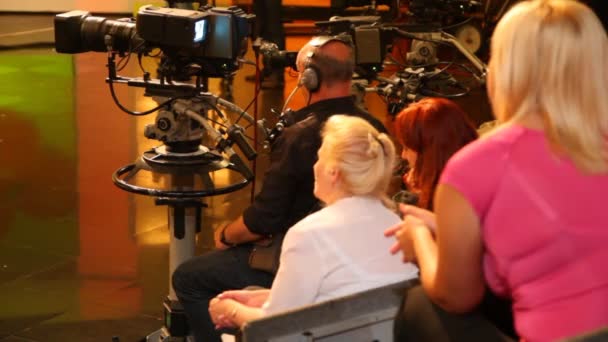 Back view of spectators and cameraman in TV studio during filming — Stock Video
