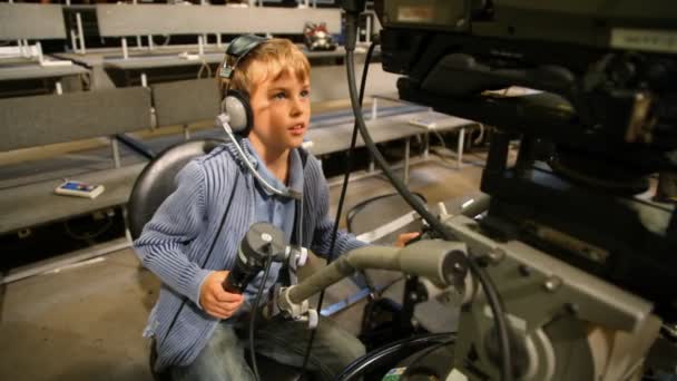 Boy in earphones operating stationary camera in TV studio — Stock Video