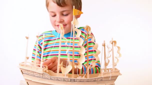Jongen stelt zeilen van speelgoed model van schip — Stockvideo