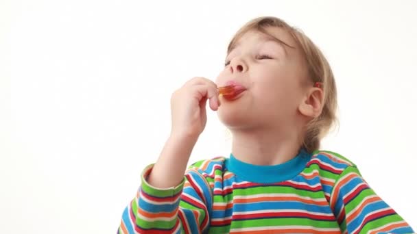 Niña comiendo piruleta, luego mira a la cámara — Vídeo de stock