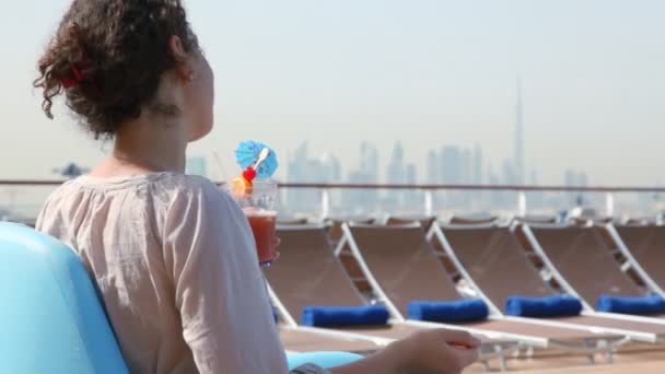 Vue arrière sur la femme assise sur le pont du navire et buvant un cocktail — Video