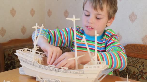 Boy with interest constructing toy model of ship — Stock Video