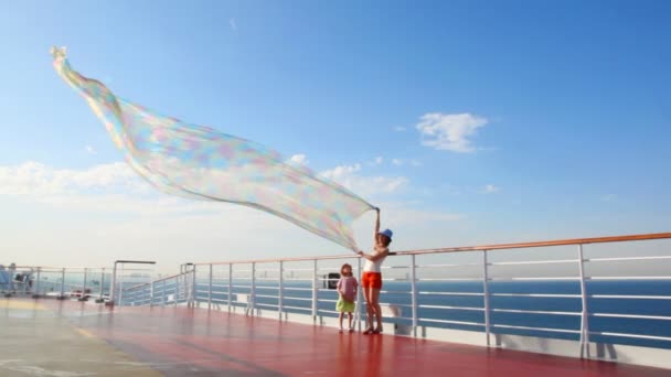 Woman with daughter stands on deck and holds fabric — Stock Video