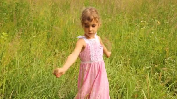 Menina está se virando segurando as lâminas de grama nas mãos — Vídeo de Stock