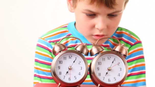 Niño sosteniendo un par de relojes de alarma sonando cerca de su oreja — Vídeos de Stock