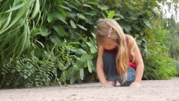 Dívka si s pískem poblíž některé rostliny — Stock video
