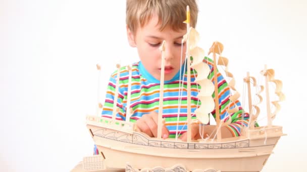 Boy with interest constructing toy model of ship — Stock Video