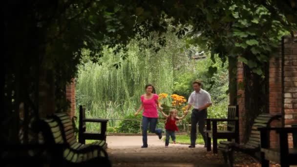 Vue de face sur parents heureux avec enfant courir dans le tunnel de la plante — Video