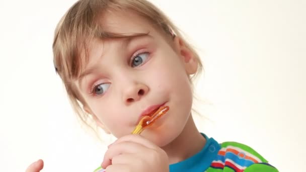 Little girl licking lollipop in chicken form — Stock Video