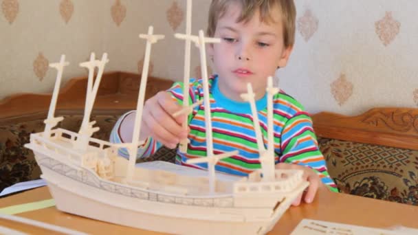 Niño con interés construyendo juguete modelo de nave — Vídeos de Stock