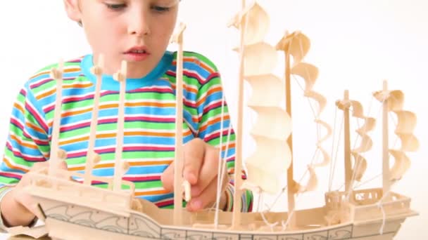 Boy with interest constructing toy model of ship — Stock Video