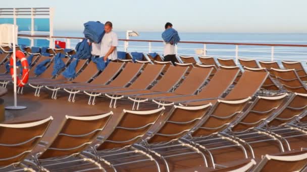 Drie personeel mannen zet handdoeken op de ligstoelen van cruiseschip in de Perzische Golf. — Stockvideo