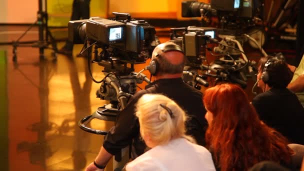 Visão traseira de cinegrafistas e espectadores no grande estúdio de TV durante as filmagens — Vídeo de Stock
