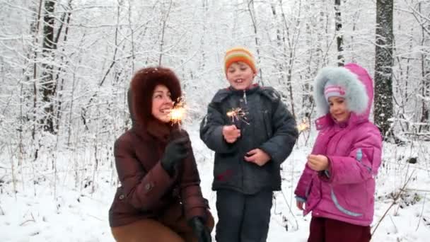Mother with boy and girl with Bengal fires in snow forest — Stock Video
