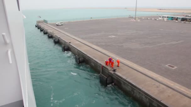 Рабочие связывают швартовочную линию корабля с причалом — стоковое видео