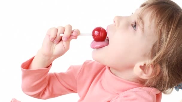 Little girl eating lollipop, then looks at camera — Stock Video