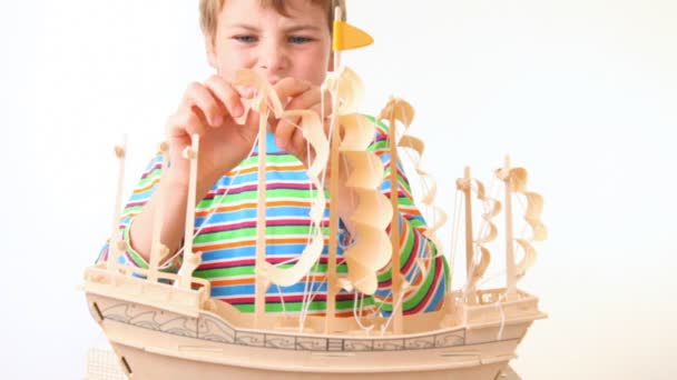 Boy sets up sails of toy model of ship — Stock Video