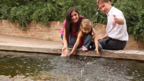 Familie makifamily maken water plons in de buurt van pond — Stockvideo