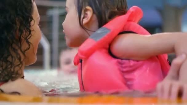 Nahaufnahme einer glücklichen dreiköpfigen Familie, die im Pool schwimmt — Stockvideo