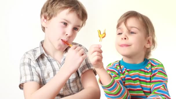 Boy and girl licking and looking at lollipops in chicken form — Stock Video