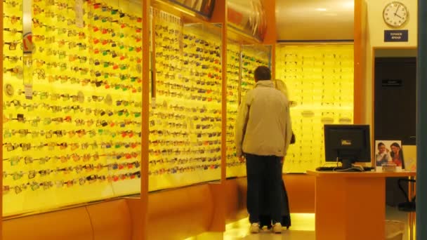 Les gens choisissent des lunettes en magasin optique — Video